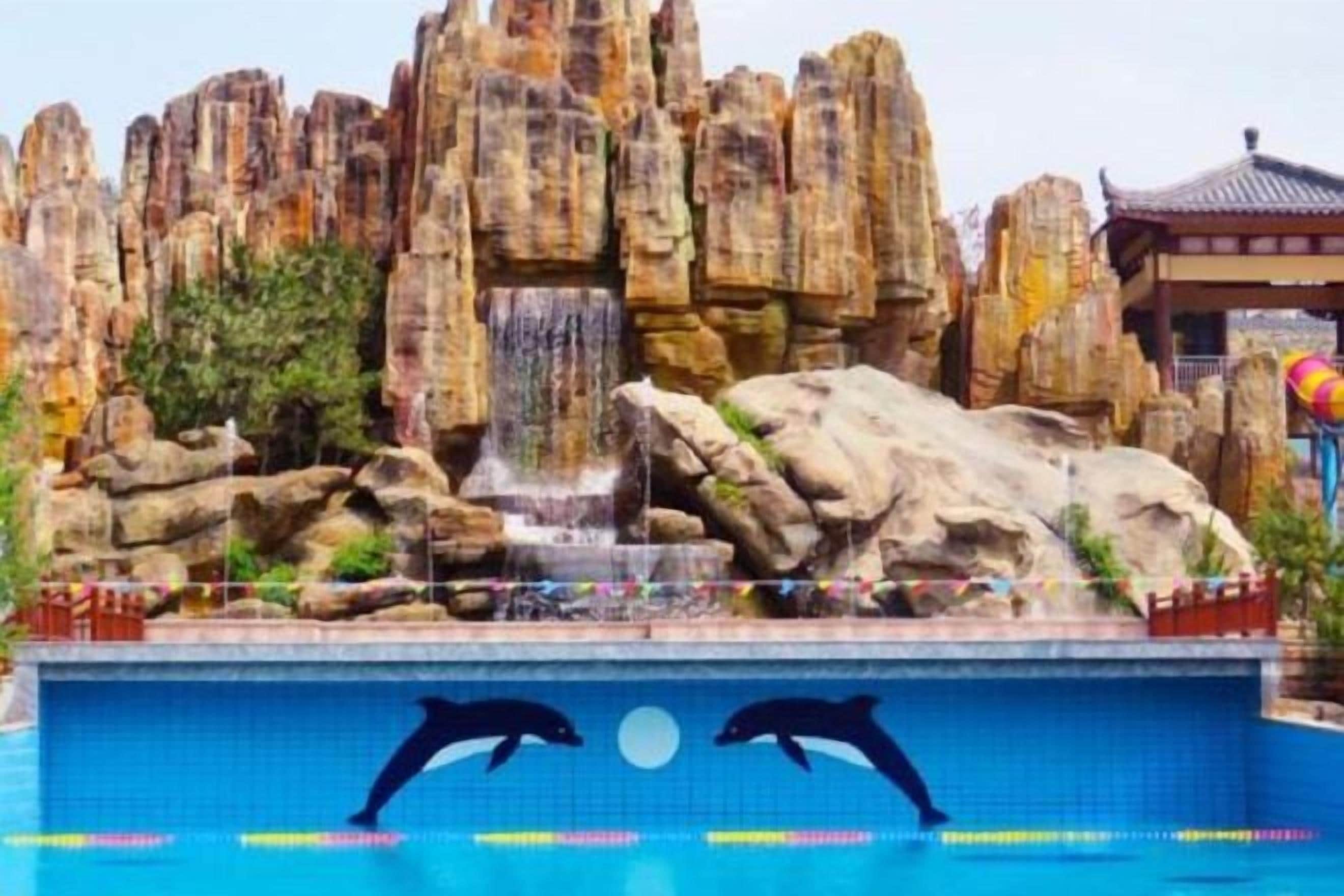 Una piscina con formaciones rocosas y una cascada al fondo.