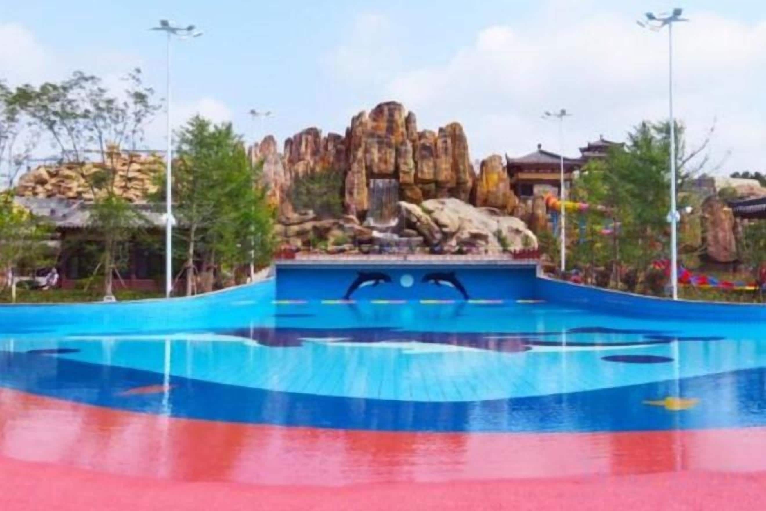 Une piscine dont le fond est constitué de rochers, entourée d’arbres et s’ouvrant sur un ciel dégagé.