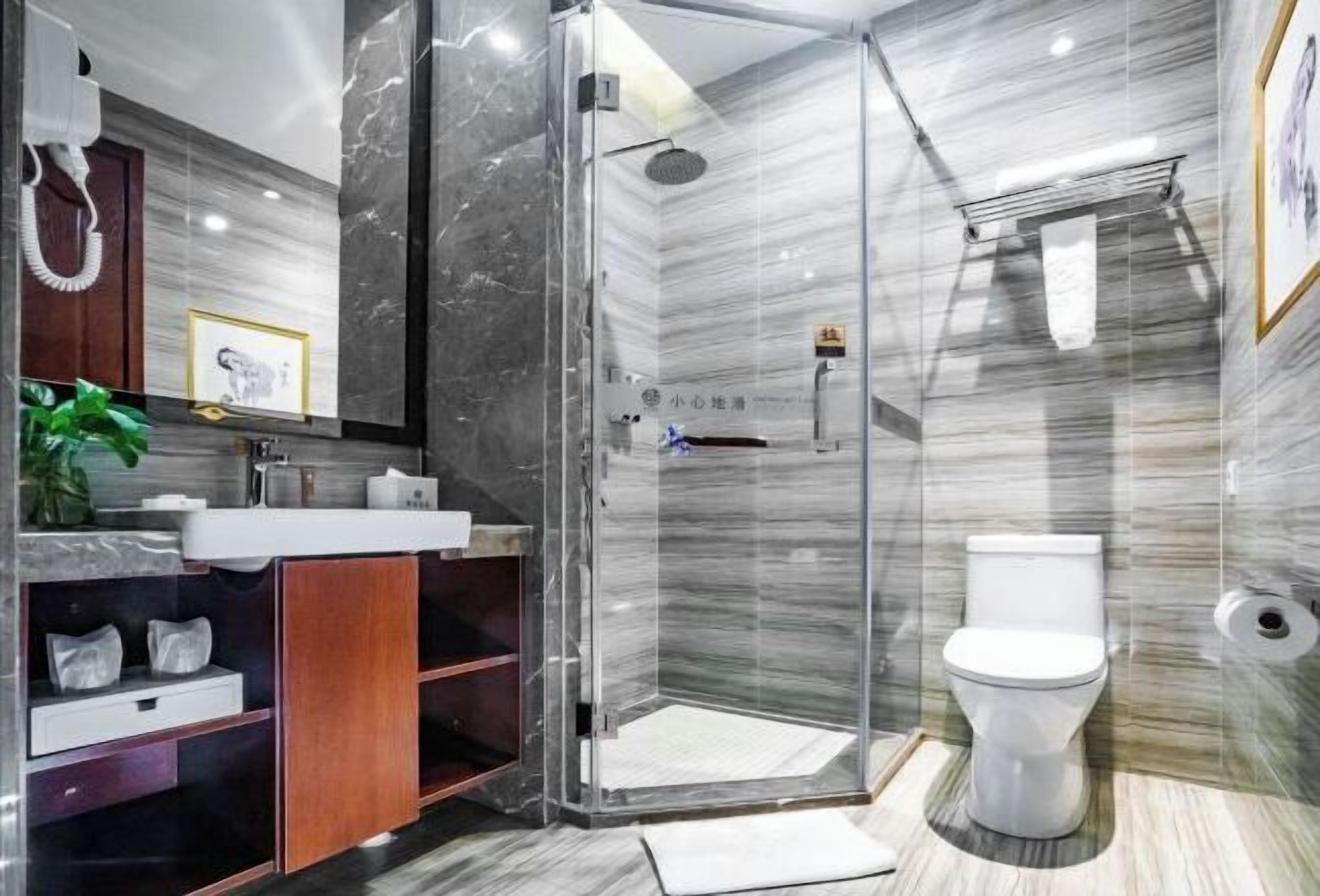Un baño moderno con ducha envuelta en vidrio, inodoro blanco y tocador con encimera de mármol.
