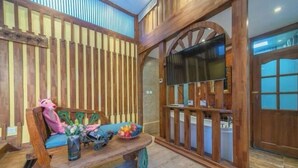 A wooden interior with a bench, a pink sculpture, and a TV. - NAXI yage hotel (Lijiang)