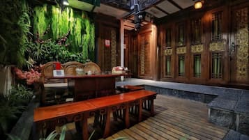 A traditional wooden interior with a wooden bench and table, a small water feature, and a decorative wall.