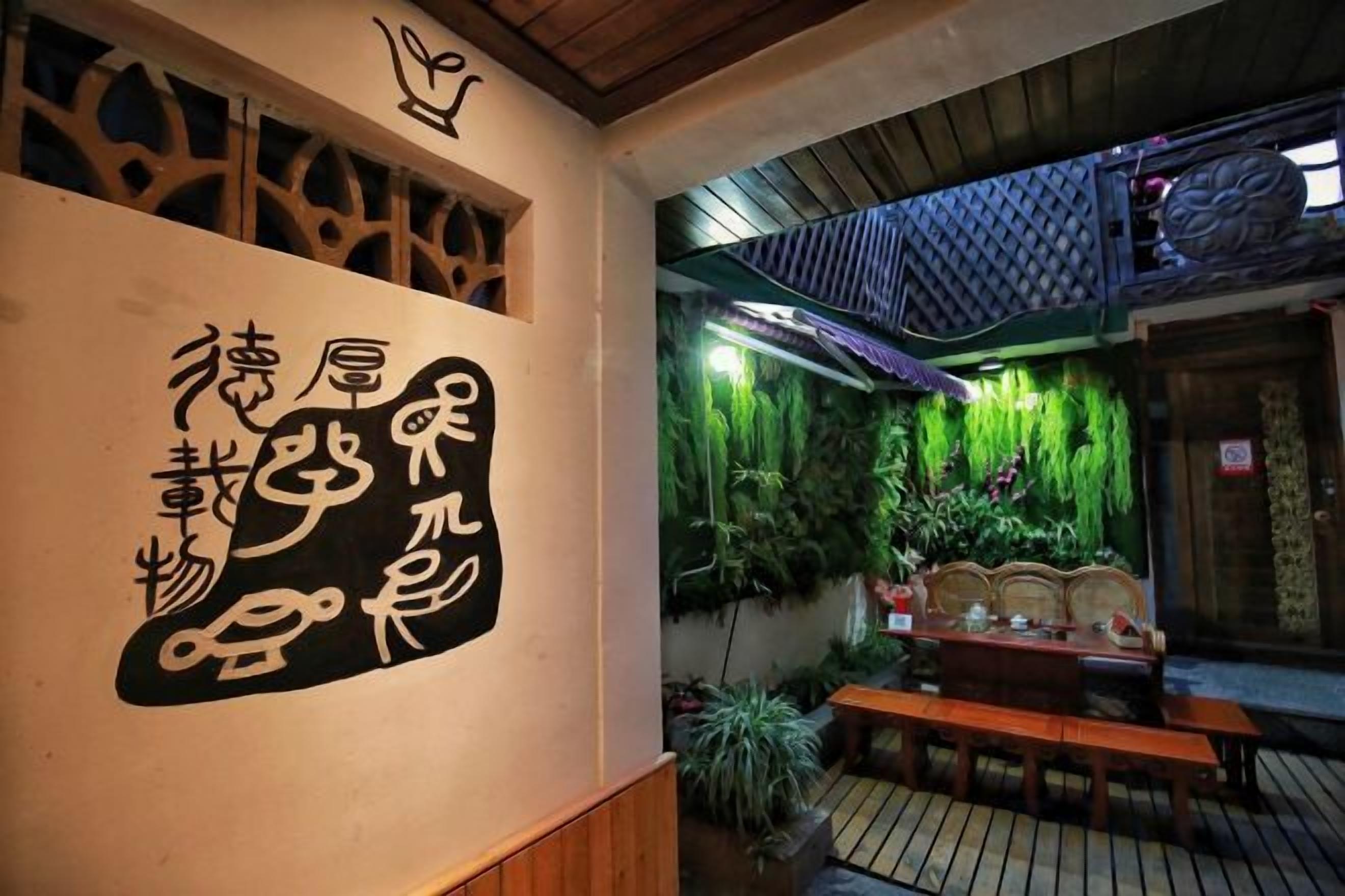 A traditional Japanese interior with tatami flooring, a wooden bench, and a wall with calligraphy.