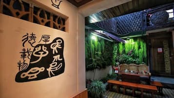 A traditional Japanese interior with tatami flooring, a wooden bench, and a wall with calligraphy.