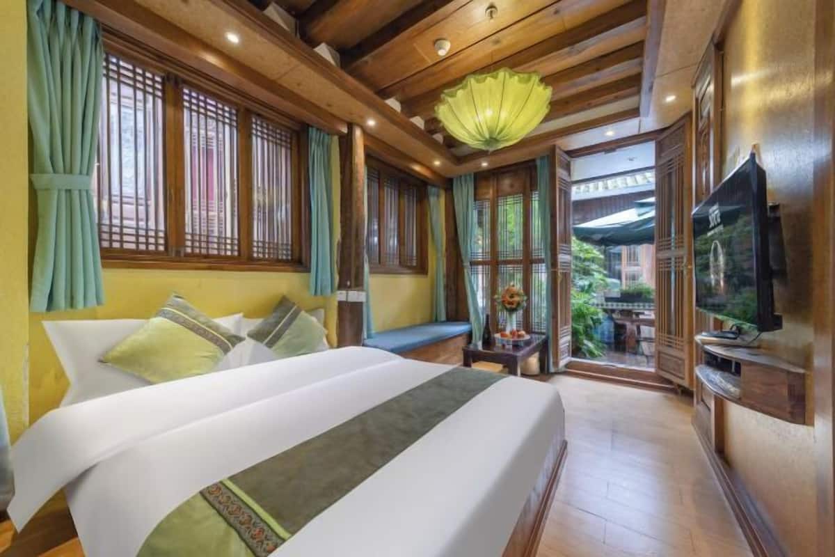 A hotel room with a large bed, wooden beams, a TV, and a view of the outdoors.