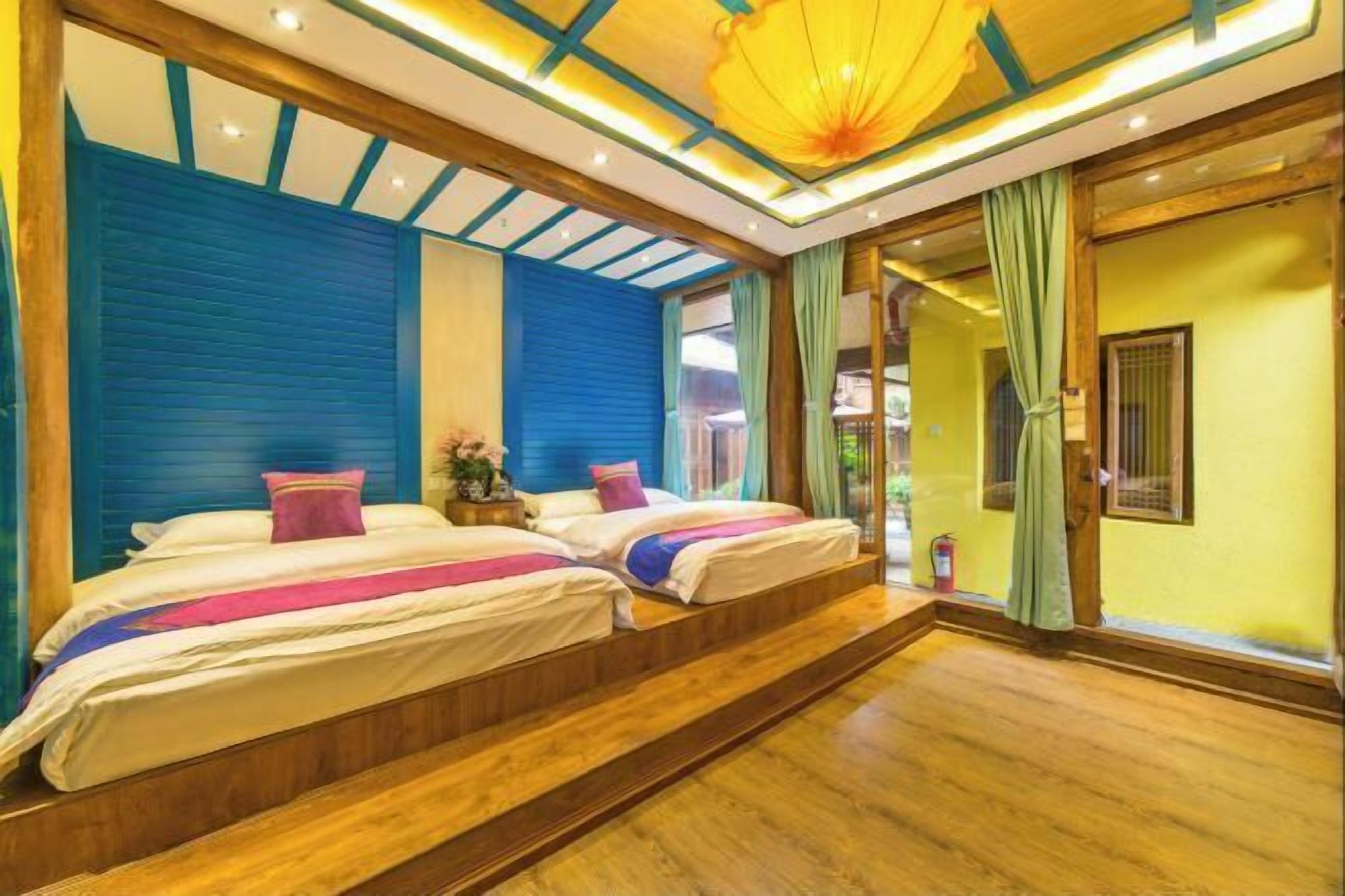 A hotel room with two beds, a wooden floor, and a ceiling with a yellow light fixture.