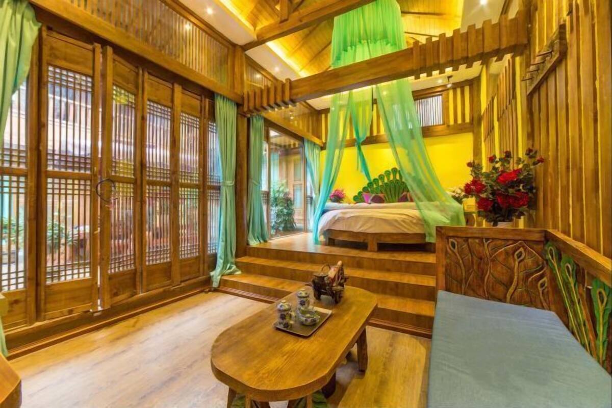 A traditional wooden room with a bed, a table with teaware, and a green canopy.