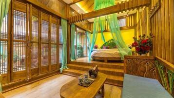 A traditional wooden room with a bed, a table with teaware, and a green canopy.