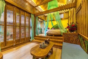 A traditional wooden room with a bed, a table with teaware, and a green canopy. - NAXI yage hotel (Lijiang)