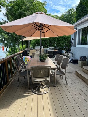 Une terrasse en bois avec une table et des chaises, un parasol et un espace barbecue.