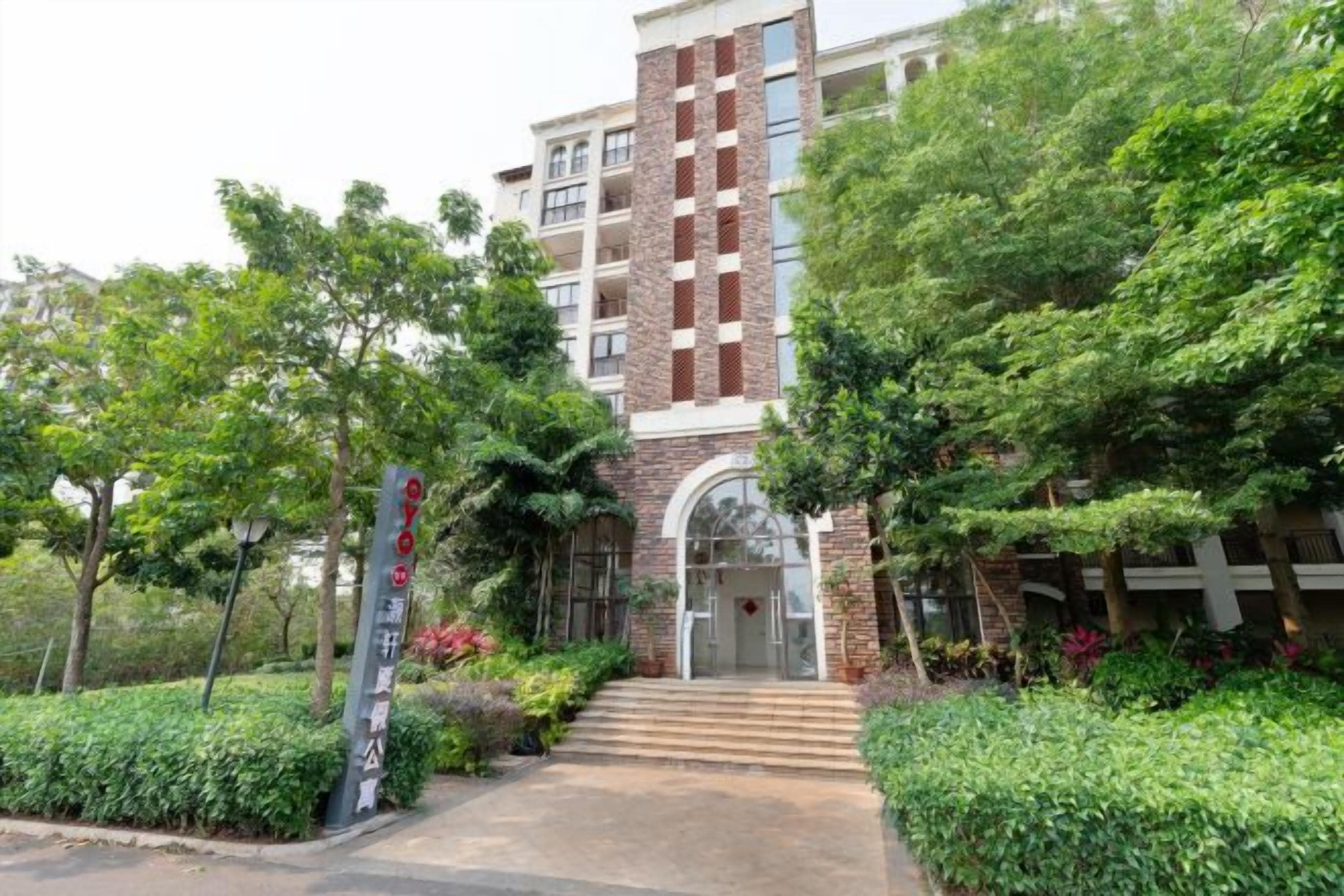 A multi-story building with a central entrance, surrounded by lush greenery and a well-maintained garden.