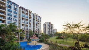 A multi-story hotel with a swimming pool surrounded by greenery. - Sincerity Holiday Apartment Hostel (Haikou)
