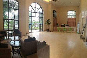 A spacious lobby with large windows, a reception desk, and seating areas. - Sincerity Holiday Apartment Hostel (Haikou)