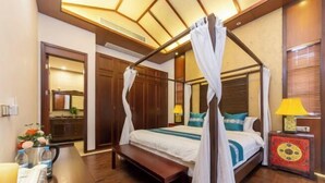 A bedroom with a four-poster bed, a bedside table with a lamp, a bench, and a decorative cabinet. - Sincerity Holiday Apartment Hostel (Haikou)