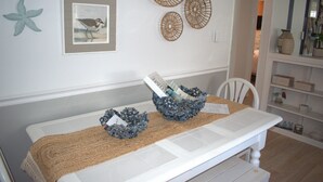 A dining area with a white table, two woven baskets, and a framed picture on the wall. - NEW LISTING!!!  Villas Quaint Coastal Cottage short drive to Beaches (Lower Township)