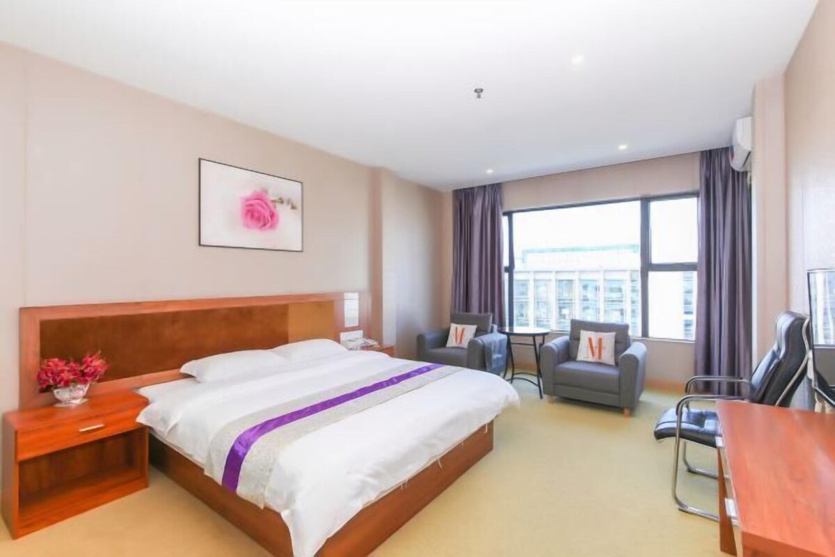 A hotel room with a bed, bedside table, chair, and a small table with a chair.