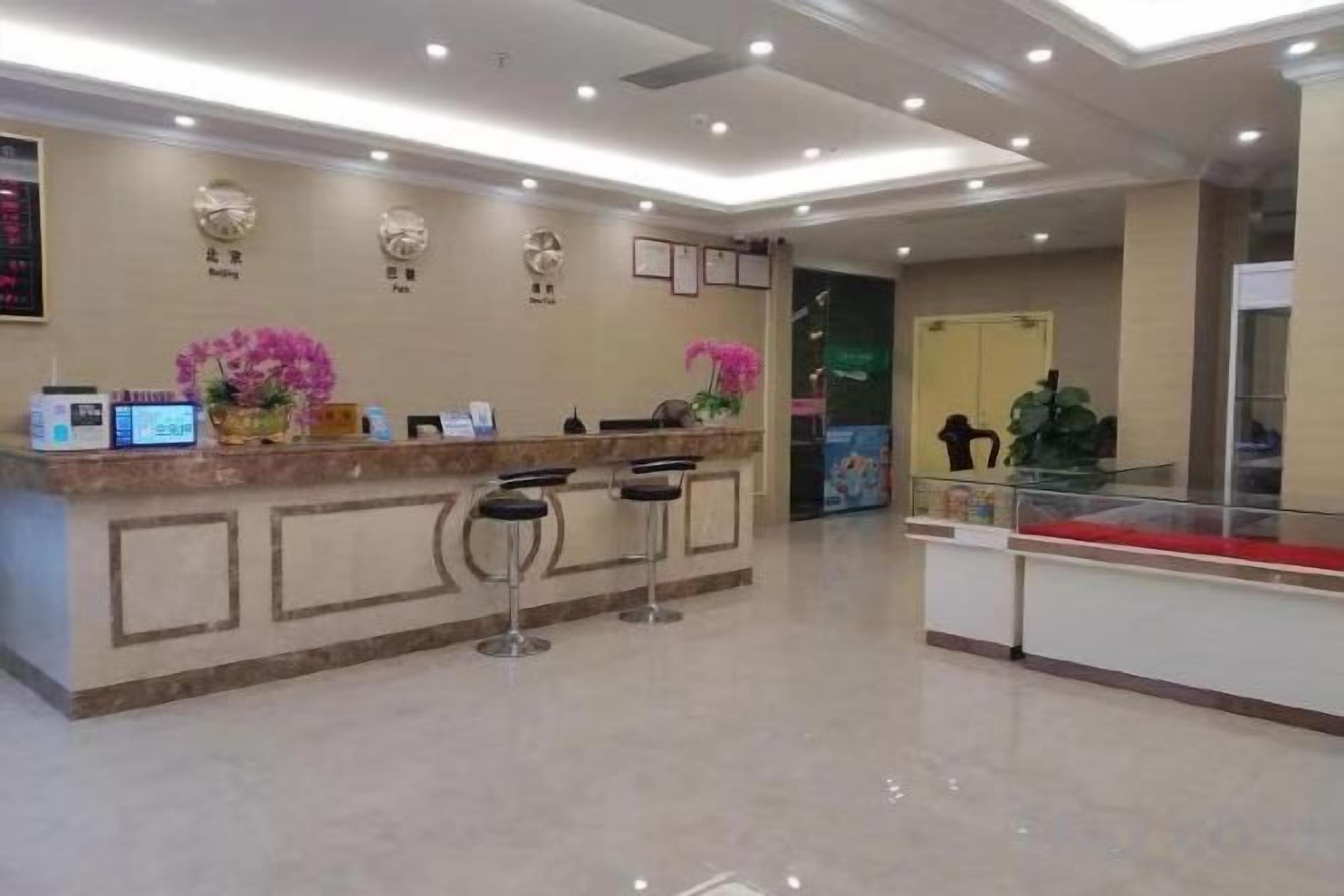 A hotel reception area with a marble counter, two bar stools, and a reception desk.