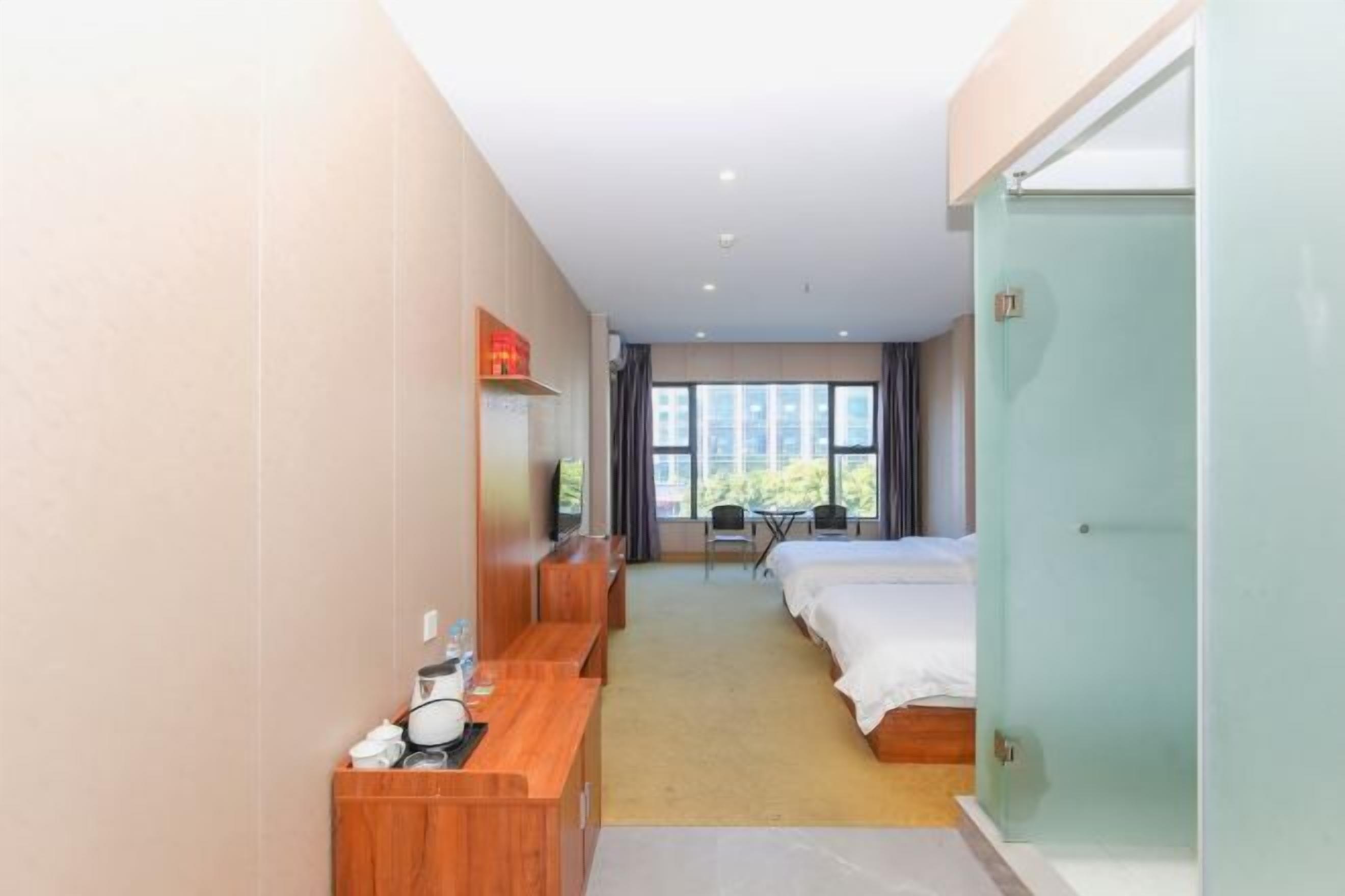 Una camera d'albergo con un letto, una scrivania, una sedia, una TV e una finestra vista edifici.