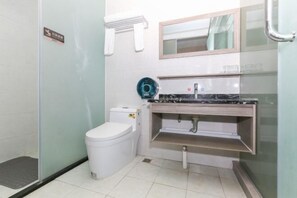 A small bathroom with a toilet, a sink, and a mirror. - Fuxiang Holiday Hotel (Zhuhai)