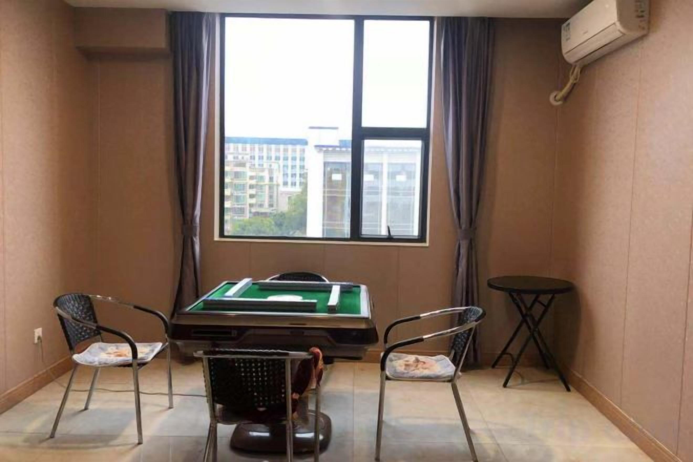 A room with a pool table, two chairs, a small table, and a window with curtains.