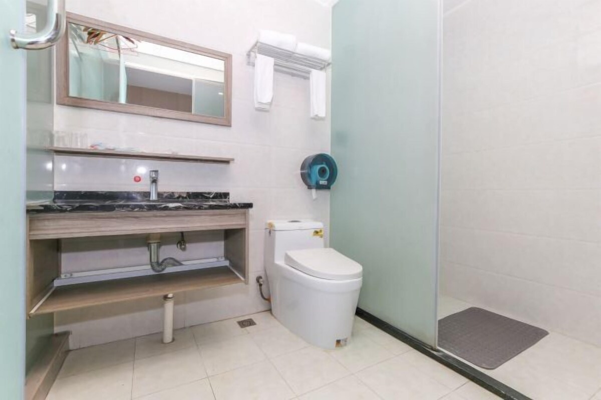 A bathroom with a toilet, sink, mirror, towel rack, and shower area.