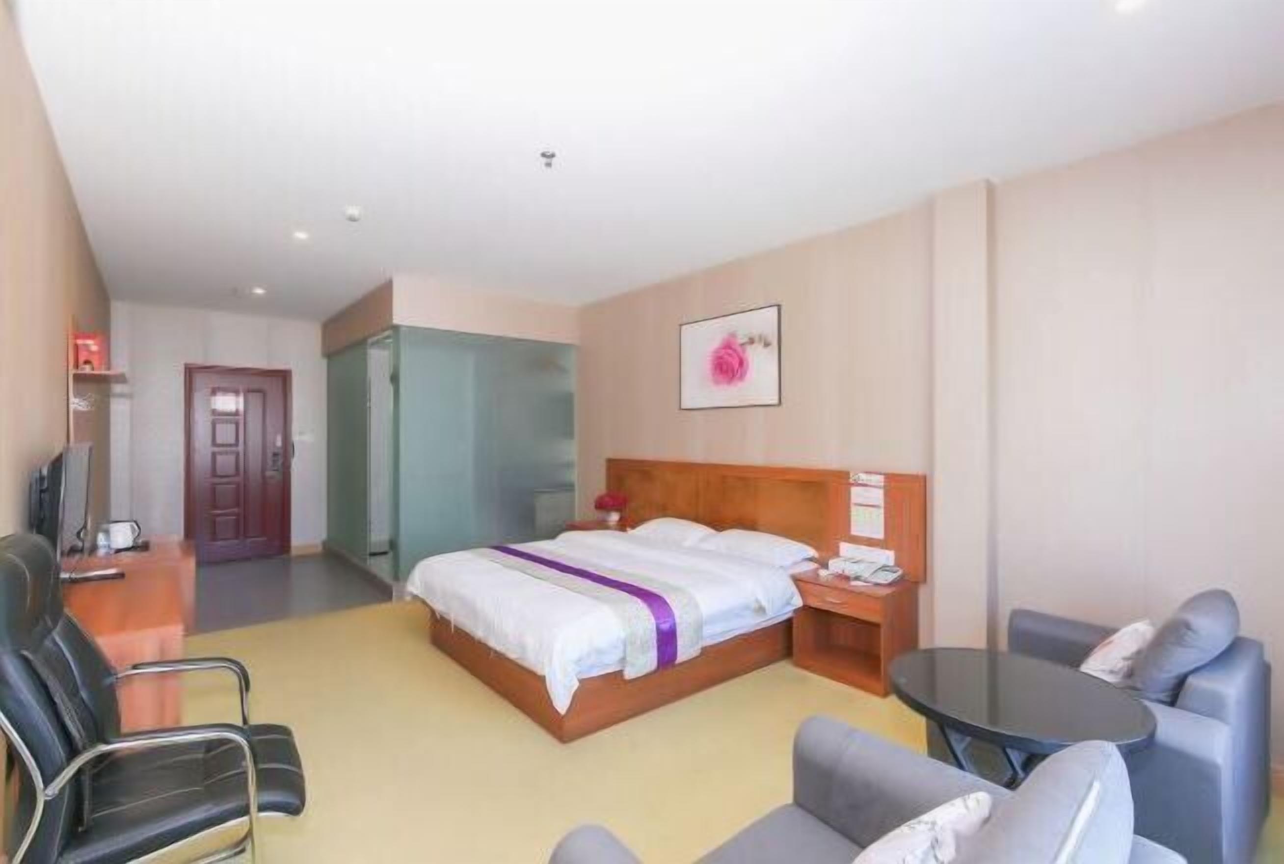 A hotel room with a bed, a desk, a chair, a sofa, and a television.