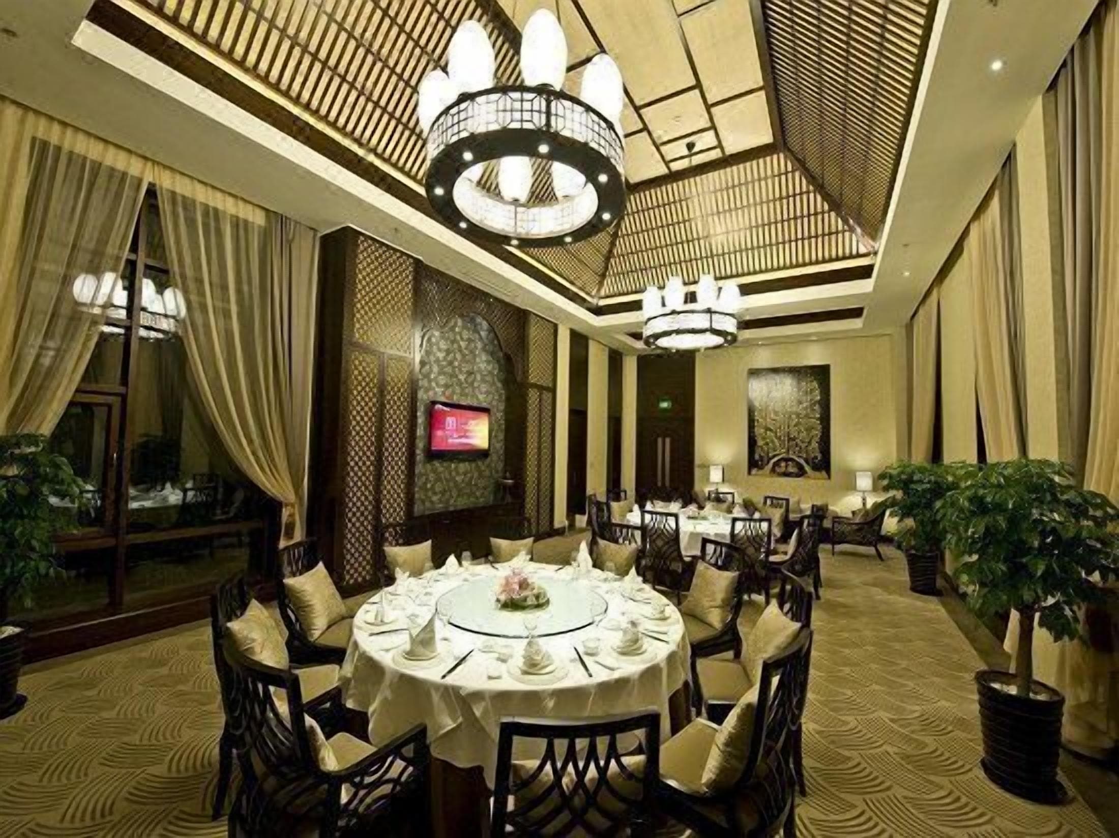 A formal dining room with a round table set for a meal, surrounded by chairs.