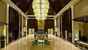 A spacious lobby with a large chandelier, a central water feature, and seating areas. - Dalian Liangyun Qiankuli Hot Spring Hotel (Dalian)