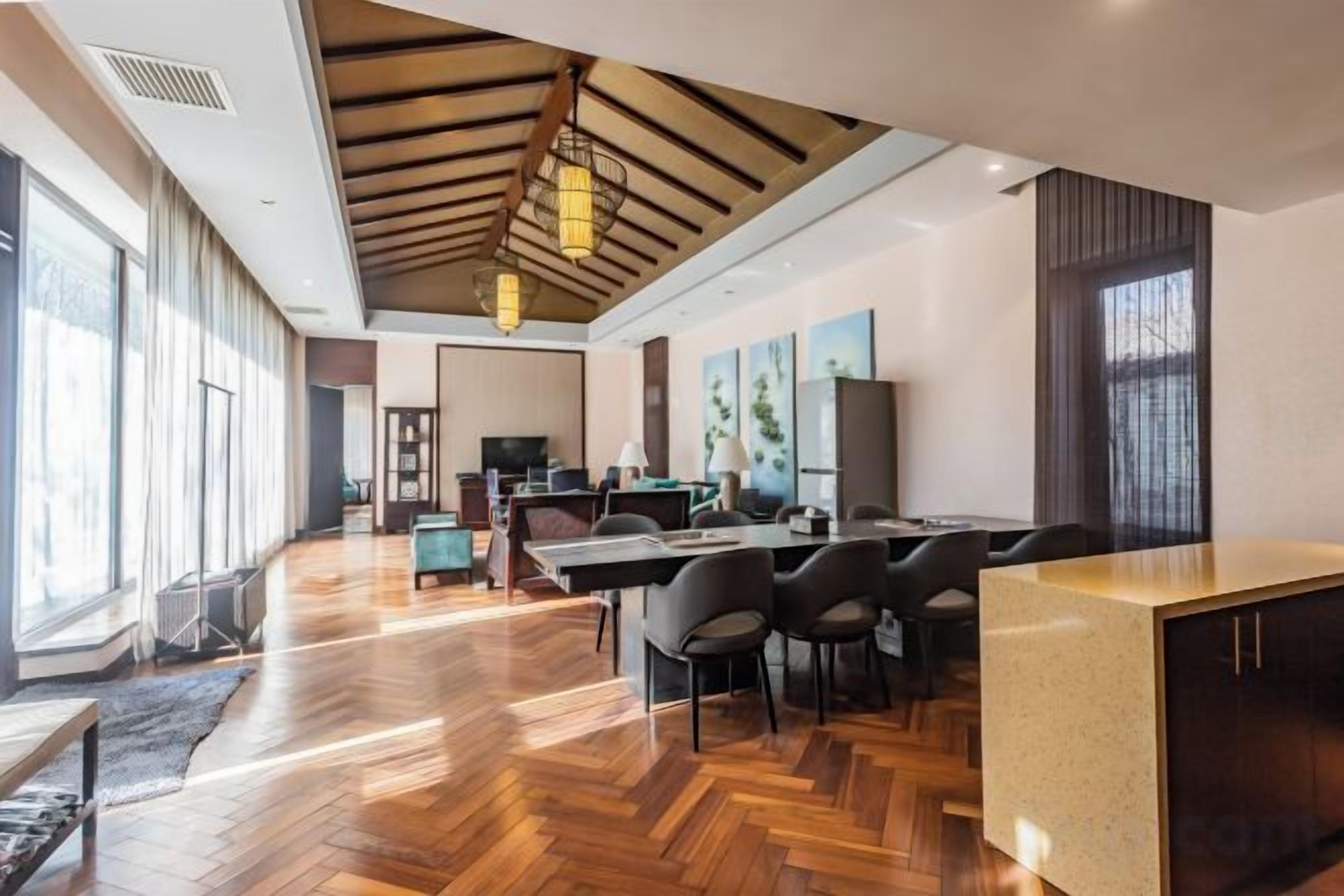 Una habitación amplia con suelo de madera, una gran mesa de comedor y una zona de cocina.