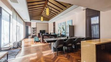 Una habitación amplia con suelo de madera, una gran mesa de comedor y una zona de cocina.