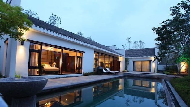 A modern house with a swimming pool, large windows, and a well-lit interior. - Dalian Liangyun Qiankuli Hot Spring Hotel (Dalian)