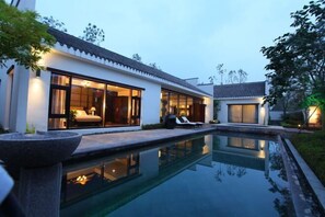 A modern house with a swimming pool, large windows, and a well-lit interior. - Dalian Liangyun Qiankuli Hot Spring Hotel (Dalian)
