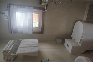 A bathroom with a toilet, a sink, a towel rack, and a window with blinds.