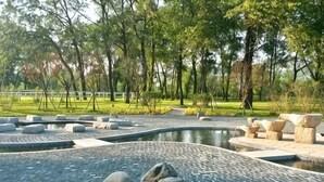 A landscaped area with a pond, seating, and trees. - Dalian Liangyun Qiankuli Hot Spring Hotel (Dalian)