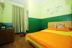 A room with a bed, a wooden desk, and a wall with a clock and drawings.