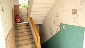 A staircase with a wooden handrail and a green wall with sketches and notes. - Shiguanguyi Youth Inn (Guilin)