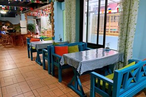 A restaurant with blue chairs and tables, a tiled floor, and a view through the window. - Shiguanguyi Youth Inn (Guilin)