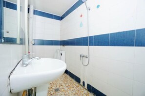 A bathroom with a white sink, a mirror, a shower, and blue-tiled walls. - Shiguanguyi Youth Inn (Guilin)
