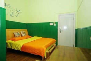 A room with a bed, green walls, a wooden floor, and a white door. - Shiguanguyi Youth Inn (Guilin)