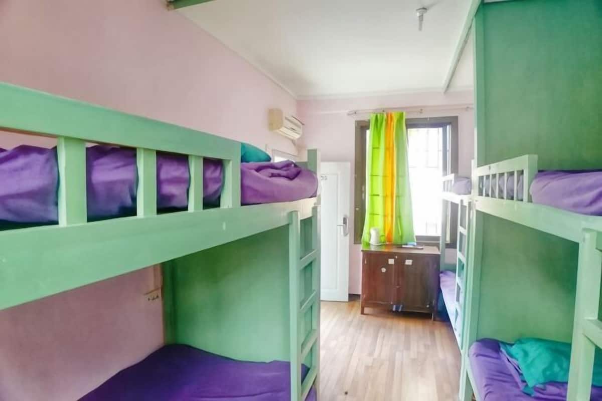A bunk bed room with a desk and a window with curtains.