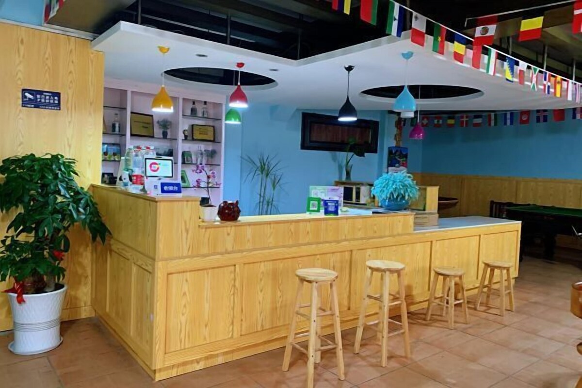 A reception area with a wooden counter, multiple stools, and a potted plant.