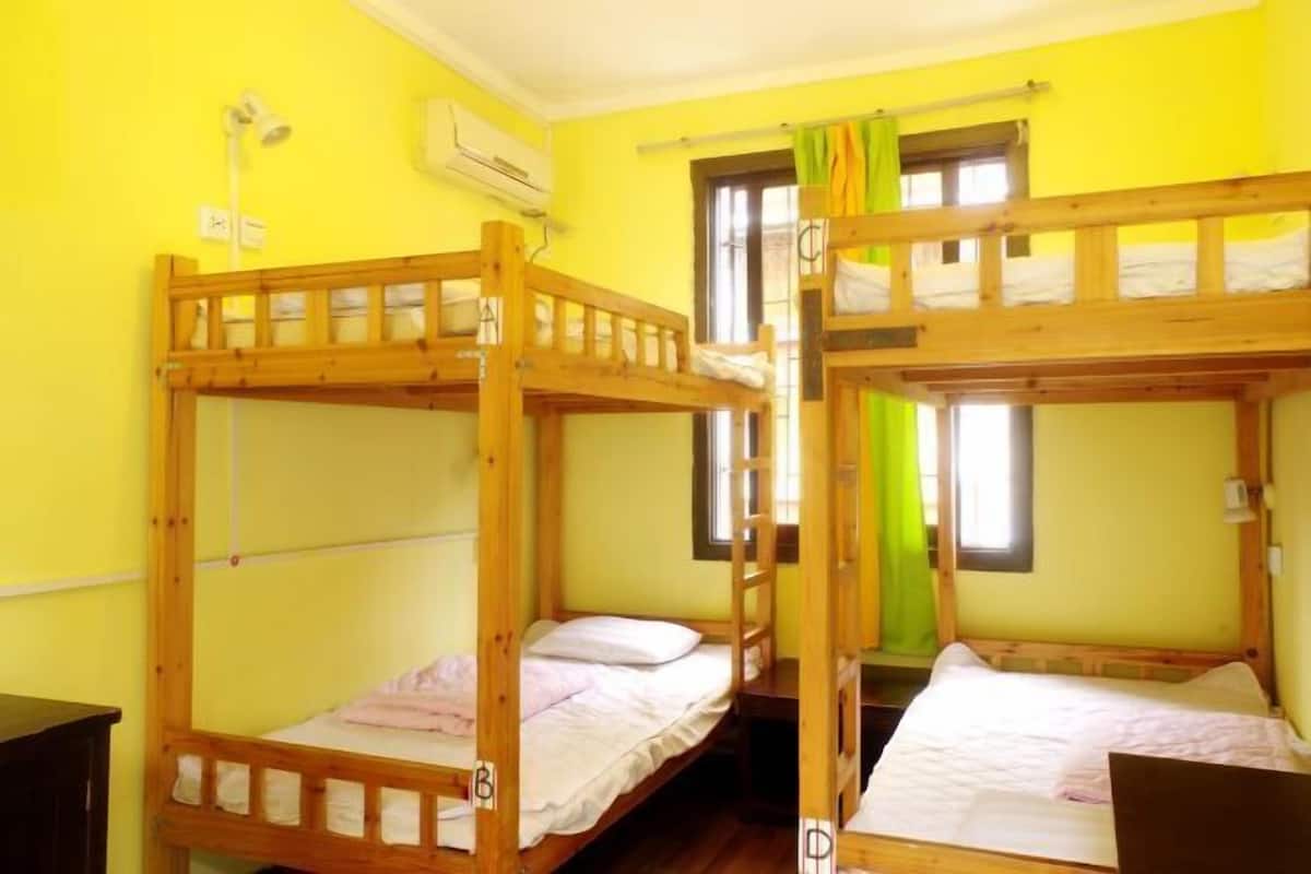 A room with two bunk beds, a window with curtains, and a desk.