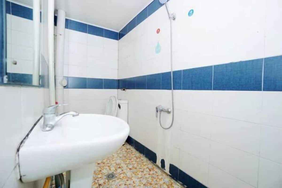 A bathroom with a white sink, a mirror, a shower, and blue-tiled walls.