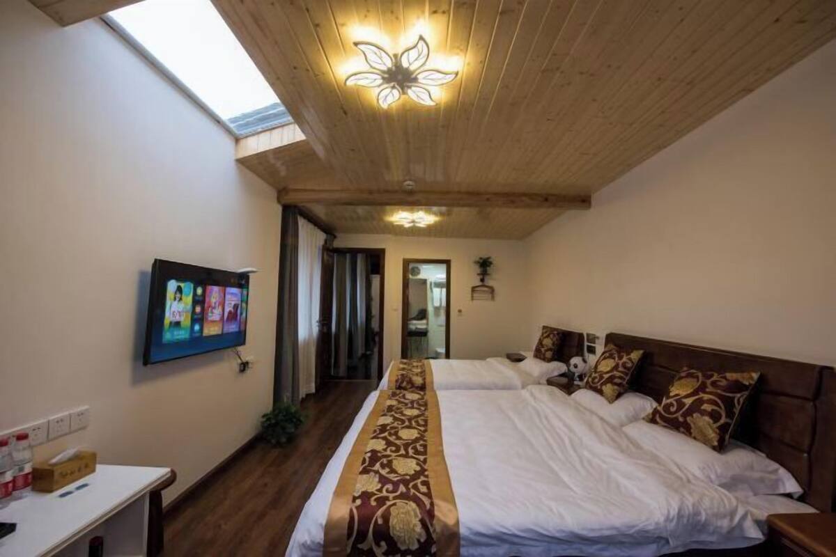 Une chambre avec un grand lit, un téléviseur fixé au mur et une lucarne.