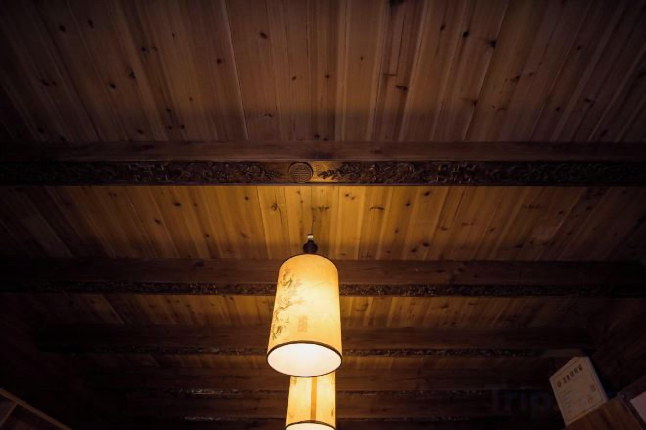 Eine Holzbalkendecke mit einer Pendelleuchte.