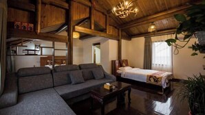 Interior de madeira com sofá, cama, lustre e planta em vaso.