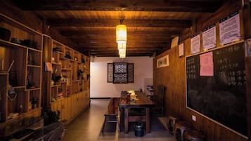 A wooden interior with a dining area, shelves, and a chalkboard with writing.