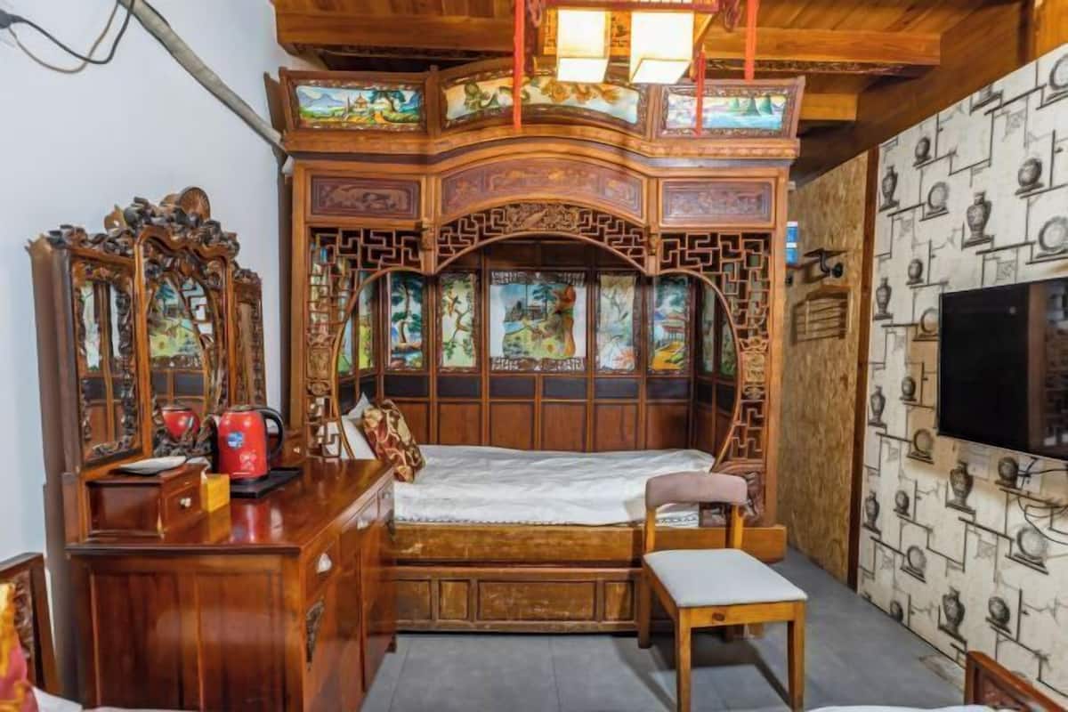 Une chambre traditionnelle en bois, équipée d’un lit, d’un bureau, d’une chaise et d’un téléviseur.