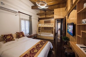A room with a bed, bunk beds, a television, and wooden walls.
