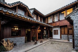 A traditional courtyard with wooden buildings, a stone wall, and a gravel ground. - Ninghai Shusong Hotel (Ninghai)