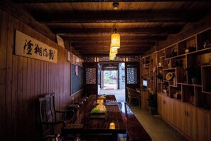 Una habitación tradicional japonesa con detalles de madera, una larga mesa de comedor y estantes con diversos objetos.
